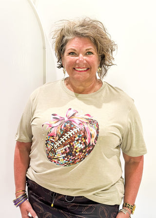 light brown soft tee with disco football with pink bow graphic on the front