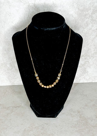 Gold necklace on a black bust against a white background