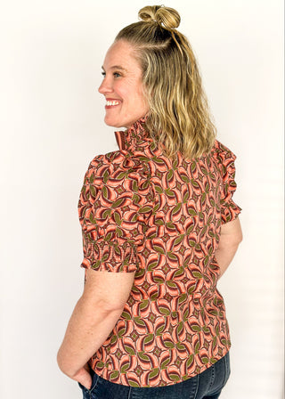 Bubble sleeve V-neck short sleeve top with terracotta, brown and green print. Ribbon detail down the front in brown and terracotta. 