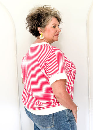 Woman wearing a red and white striped shirt and blue jeans against a white background