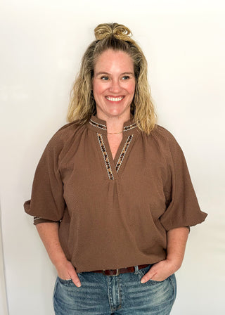 Chocolate brown v-neck top with 3/4 length sleeve, leopard lace detail around sleeve, collar, and v-neck.