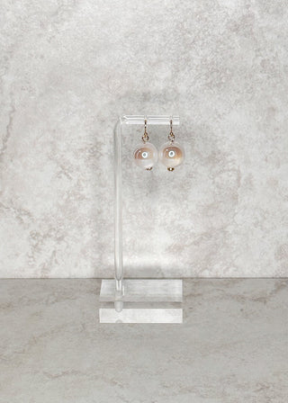Earring stand with clear/white fish hook earrings on a gray marble background