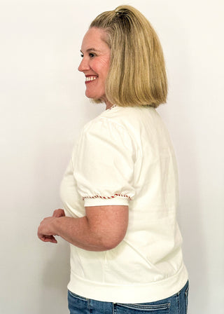side view of woman modeling a short sleeve puff sleeve top with fabric gingerbread man with sequins and embroidery details