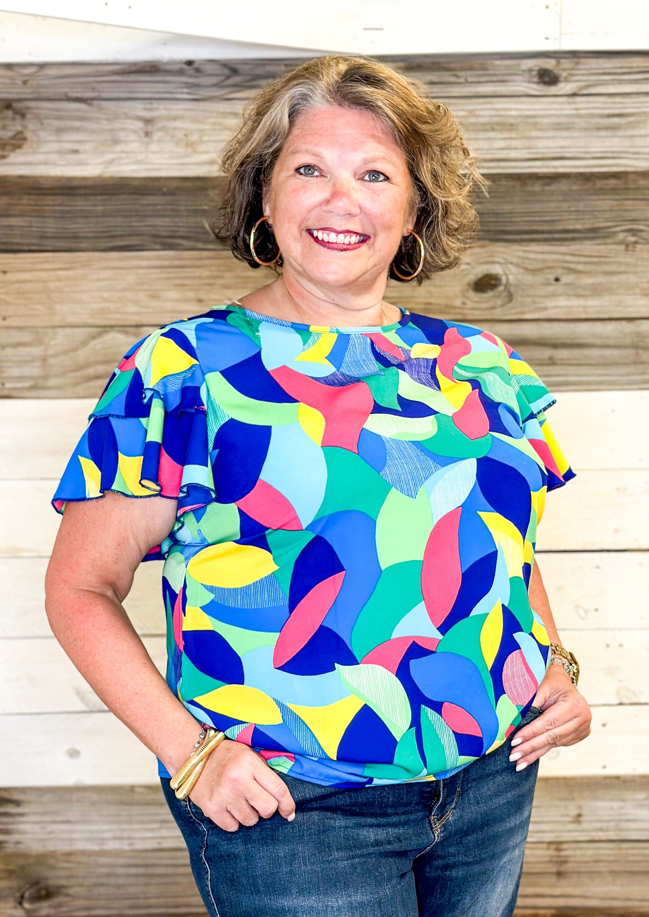 bright colors form a geometric pattern - no stretch recommended to size up - double ruffle sleeve - short sleeve top - colors of blues, pink, green, yellow