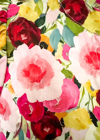 V-neck floral puff sleeve top with bright blooms in pink, wine, gold and green. short sleeve, ruffle collar with 3 button closure. 