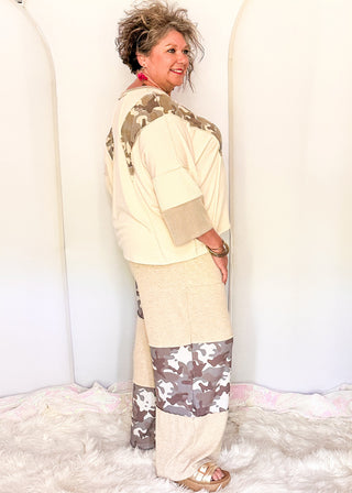 Wide leg pants featuring alternating taupe knit and camo print patchwork panels with an elastic waistband and side pockets.