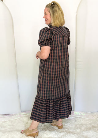 side view of woman wearing a plaid midi dress with puff sleeves and a tiered ruffle hem