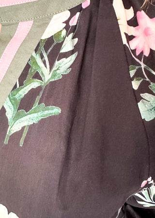 dark navy top with florals in light pink and white with green leaves.  3/4 length sleeve and v-neck with contrast detail in dusty blue and light pink. 