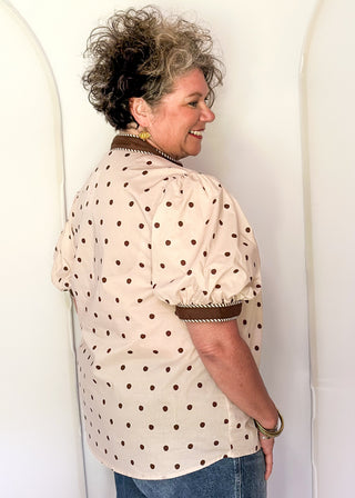 woman wearing Ecru button up top with brown polka dots. 
