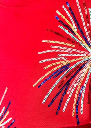 Close up of red short sleeve top with 2 sequin firework bursts.