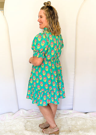 Mint green floral dress with colorful pink flowers, featuring short puff sleeves, ruffled neckline, smocked waist, and flowy skirt.