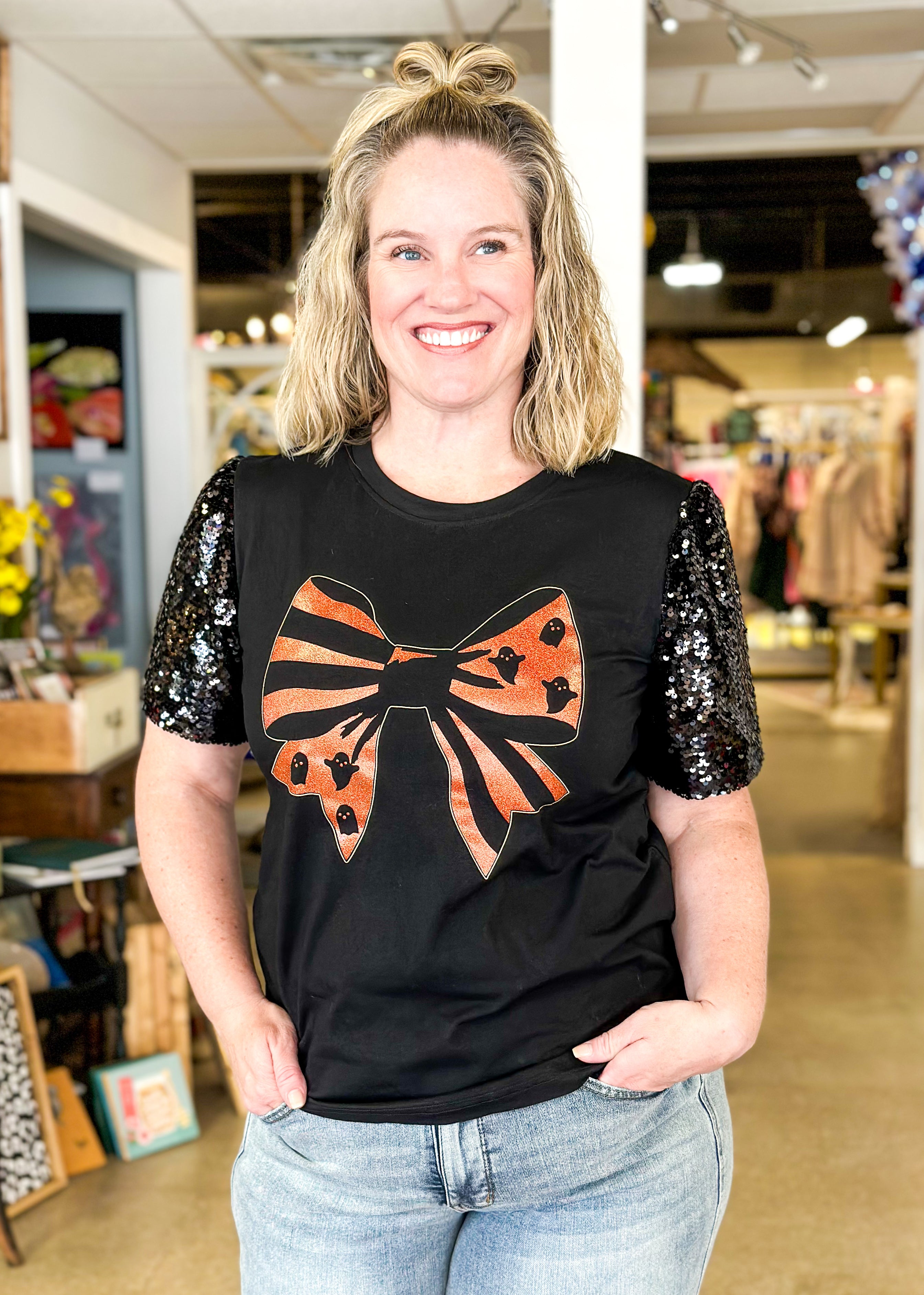 black top with black sequine short sleeves, orange glitter bow with ghosts and stripes