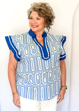 Patterned short-sleeve top in blue with contrast trim with scallops, v-neckline.