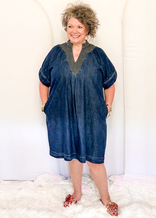 Women's dark blue denim dress featuring statement puff sleeves and contrast stitched detailing around the neckline.