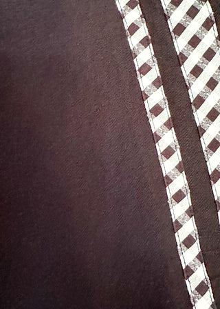 Close up of women's black top featuring a gingham contrast neckline, loose silhouette, and subtle puff sleeves