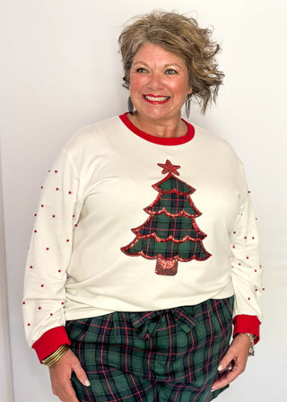 White long sleeve Christmas top with red neckline and cuffs, featuring a plaid Christmas tree appliqué with red sequin trim on the front. Red pearl accent the sleeves for a festive touch.”