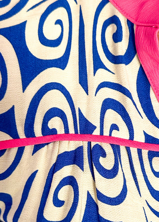 close up of royal blue swirl print top featuring pink contrast trim, puff sleeves, and lightweight relaxed fit.