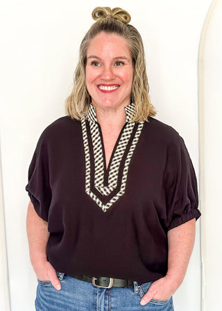 Women's black top featuring a gingham contrast neckline, loose silhouette, and subtle puff sleeves