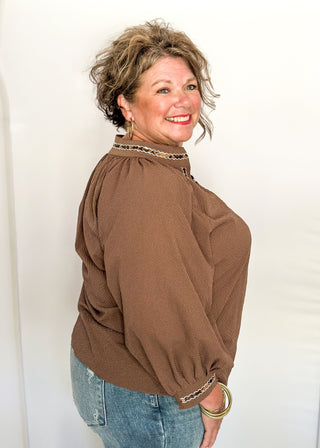 Chocolate brown v-neck top with 3/4 length sleeve, leopard lace detail around sleeve, collar, and v-neck.