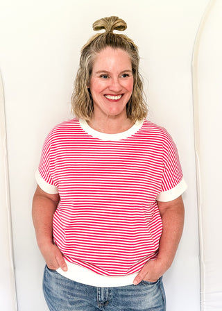 Woman wearing a red and white striped shirt and blue jeans against a white background