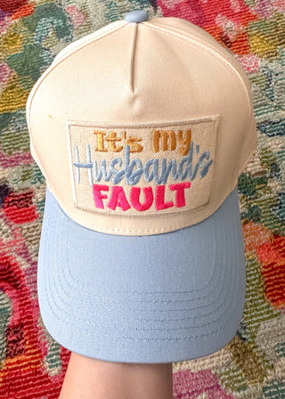 Neutral snap back cap with pastel blue bill and “It’s My Husband’s Fault” embroidered patch