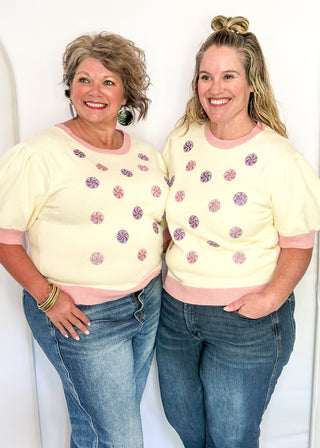 Cream short sleeve sweater with puff sleeves, pink trim, and sequin peppermint candy accents on the front