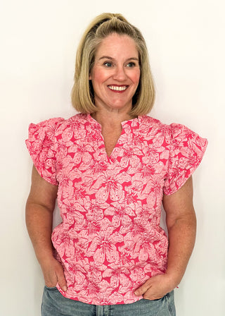 woman wearing pink jacquard flutter sleeve blouse with a floral pattern