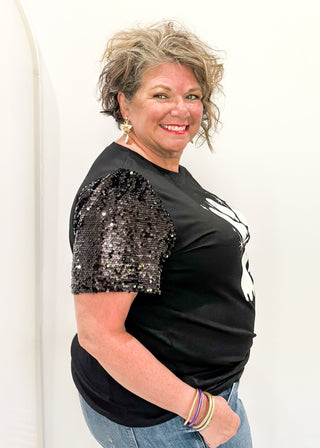 Black short sleeve top with sequin sleeves. Multiple white ghosts on the front