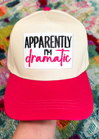 Snapback canvas hat with natural canvas body, hot pink bill. Large white patch with "Apparently I'm (embroidered in black) dramatic" (embroidered in hot Pink) 