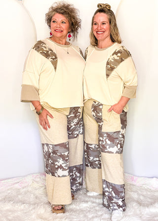 Wide leg pants featuring alternating taupe knit and camo print patchwork panels with an elastic waistband and side pockets.