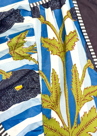 Close up of blue and white striped midi dress with dark blue floral print, flutter sleeves, contrast V-neckline, and a flowy tiered hem