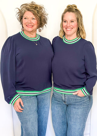 Navy long-sleeve top with green-and-white striped trim at neckline, cuffs, and hem.