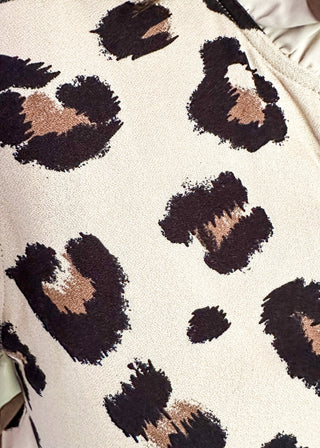 Beige short sleeve button-up blouse with bold black leopard spots and layered ruffle trim on the neckline and sleeves.