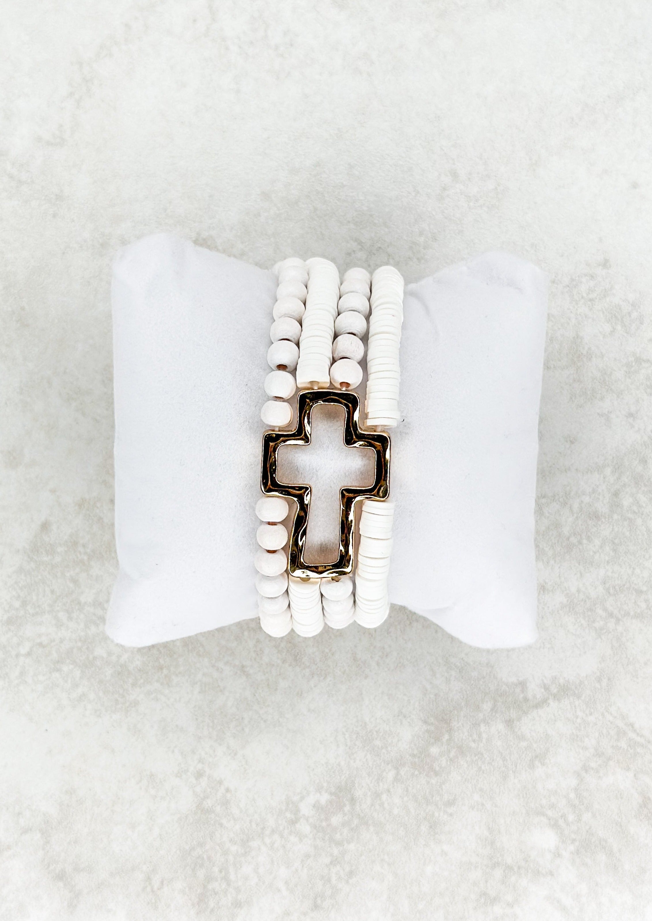 Four strand white beaded stretch bracelet attached to open gold cross.