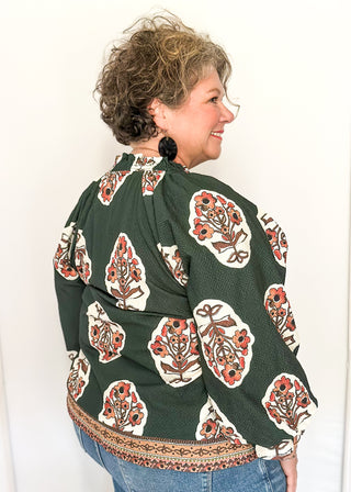 Forest green boho print top featuring smocked collar large floral bundles and colorful border trim.