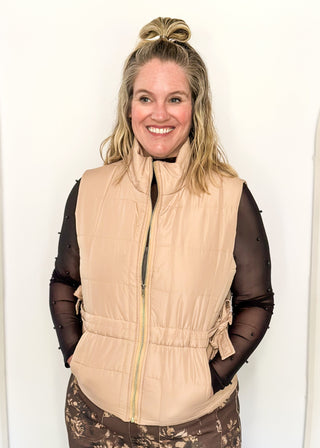 Beige puffer zip up vest with sides that tie and pockets