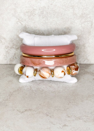 Set of 4 blush white and gold bracelet set displayed on a stand 