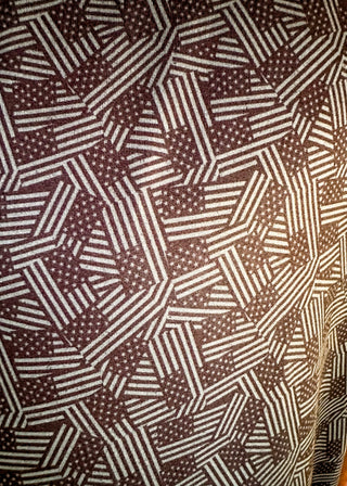 A close-up of a patterned fabric with an abstract geometric design in dark brown and off-white, featuring stripes and small dots.