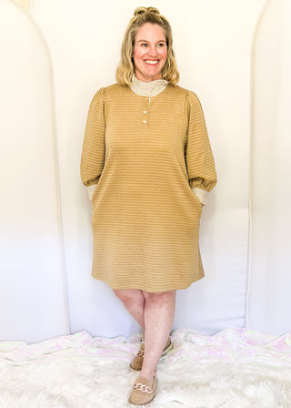 Long-sleeve textured neutral tan dress with a striped ruffle neckline, partial button front, and matching striped sleeve cuffs