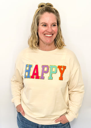 Lightweight cream long-sleeve top with colorful chenille patch letters spelling “HAPPY”