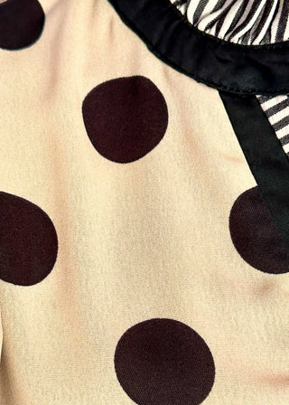 Close up of cream flowy polka dot dress with tiered layers and contrast striped neckline detail