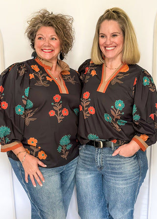Black floral blouse with colorful flowers, contrast tan and orange trim, and ruffled neckline