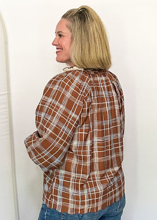 side view of woman modeling a brown and blue plaid blouse with ruffle collar and 3/4 sleeves.