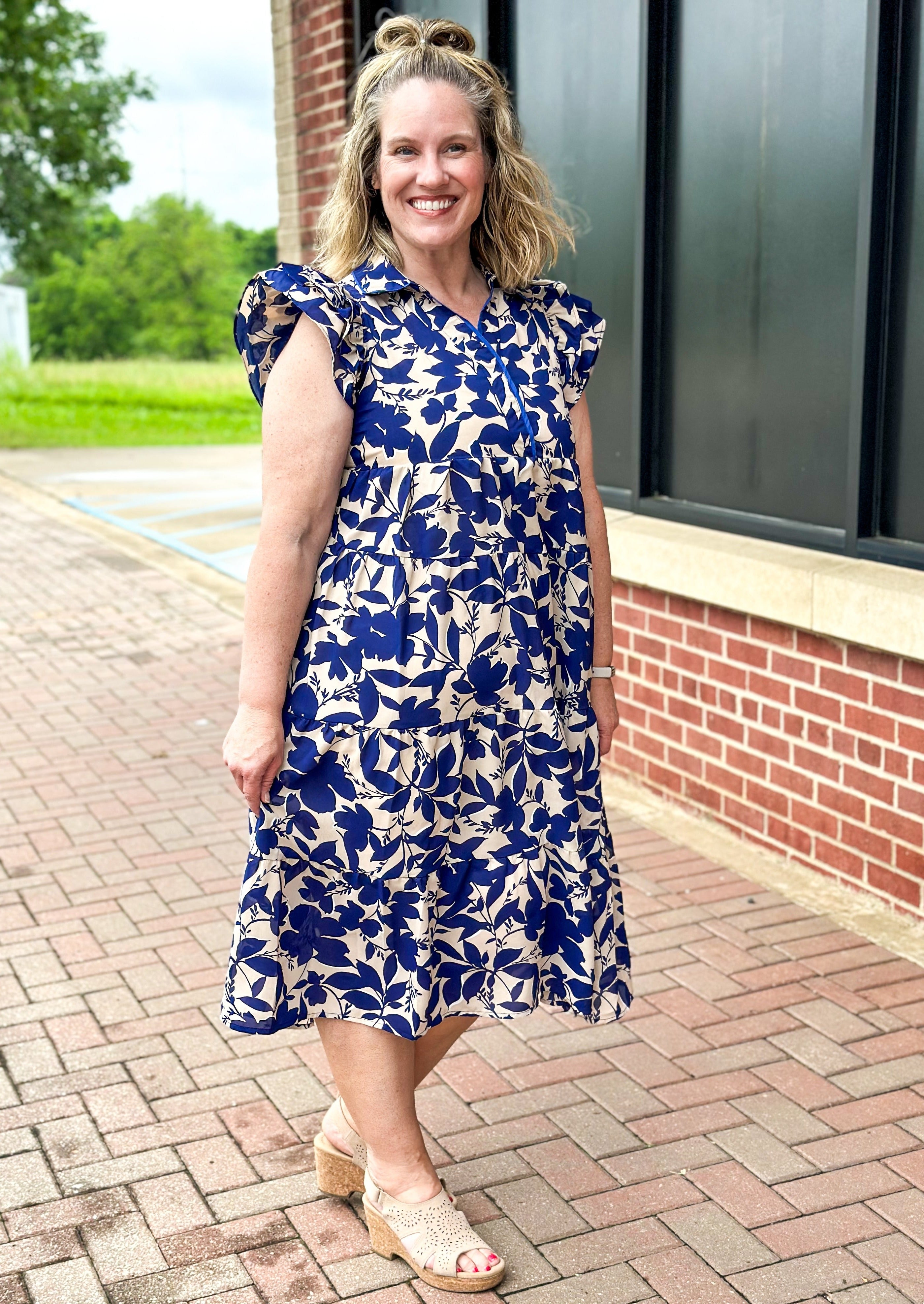 Navy floral tiered midi dress on light tan background - collar - multi ruffle sleeve - piping detail on top