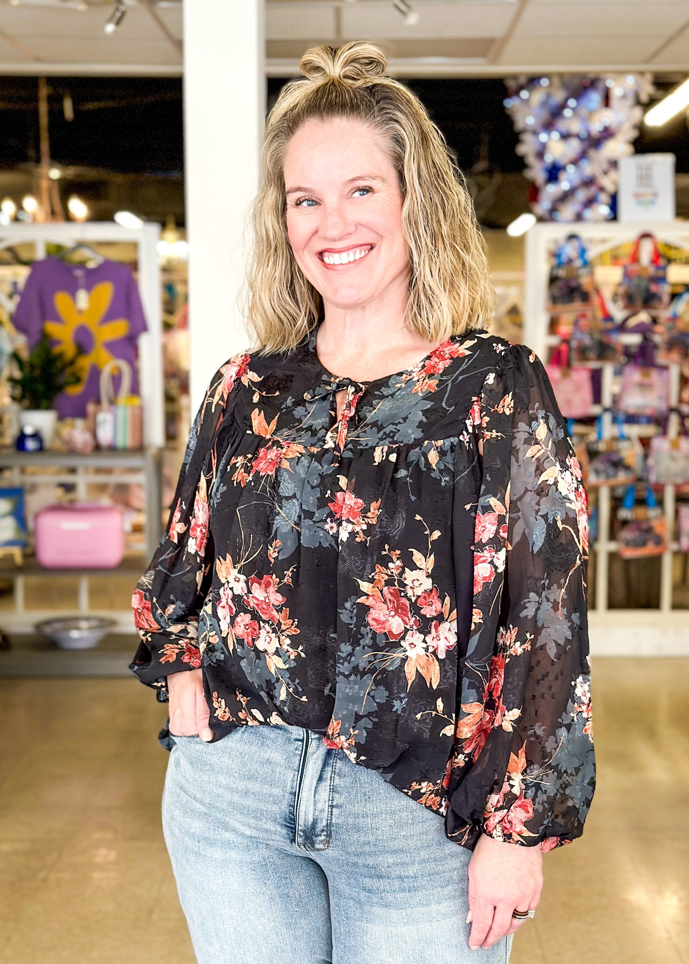 black floral top with sheer long sleeves - flowers are rust, orange and bluish gray, tie neck lined