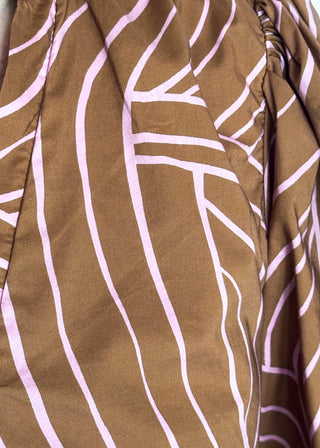 A close-up of a brown fabric with a light pink abstract wavy line pattern.