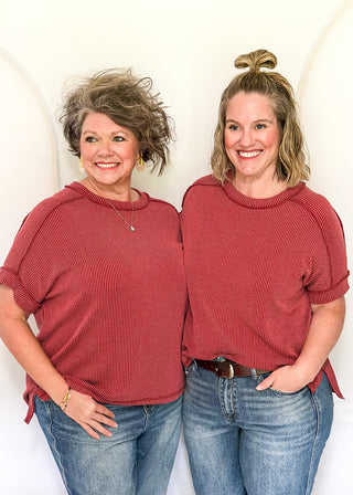 2 women wearing a red sweater and blue jeans against a white background