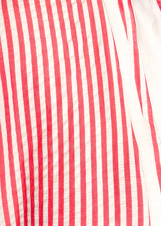 Close up of striped seersucker top in pink and white with short sleeves, relaxed fit, and split neckline.