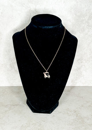 Necklace with a golf cart pendant on a black velvet bust against a white background