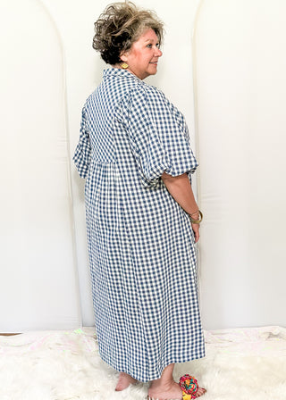 Woman wearing long blue gingham dress with short sleeves